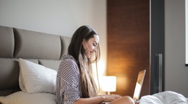 Ein Foto einer schönen Frau, die im Bett sitzt, während auf ihrem Laptop